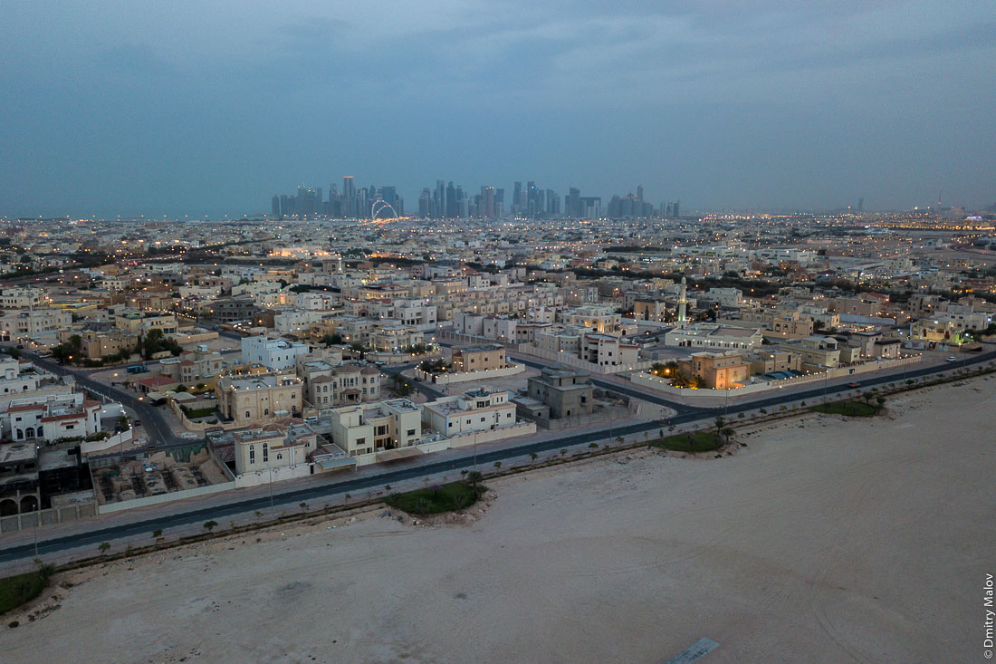 Doha, Qatar - an aerial drone photo of a skyscraper city bordering the desert. Катар, Доха — аэрофотосъемка с дрона города небоскрёбов граничащего с пустыней