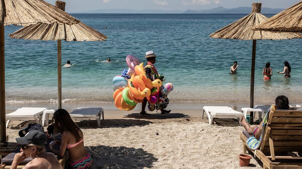Отдыхающие и продавец игрушек на городском пляже Алимос в пригороде Афин