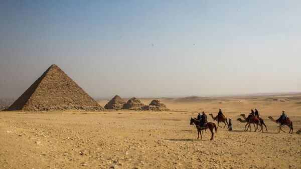 Группа туристов верхом на лошадях и верблюдах во время экскурсии к древнеегипетским пирамидам в Эль-Гизе, пригороде Каира